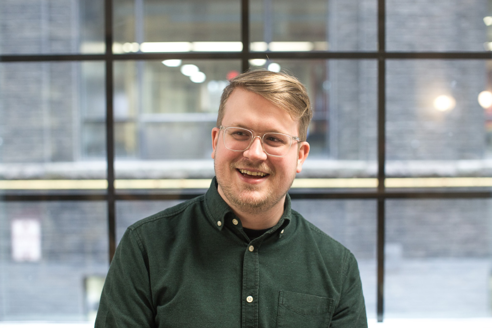 PathFactory employee Evan, smiling man with blonde hair and glasses, wearing a dark green collared shirt